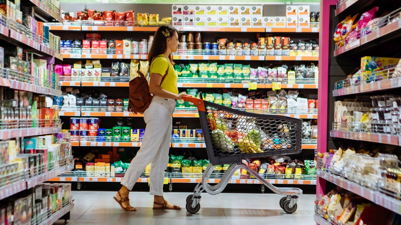 Frau mit Einkaufswagen fährt durch einen Supermarkt