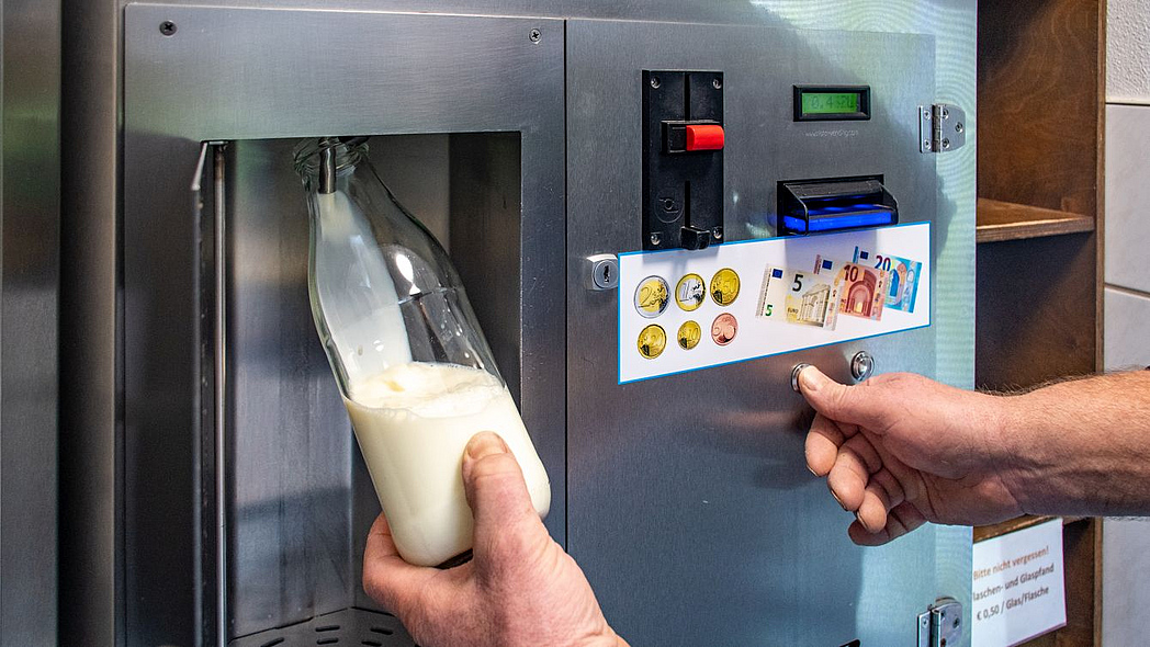 An einem Milchautomat wird Milch gezapft