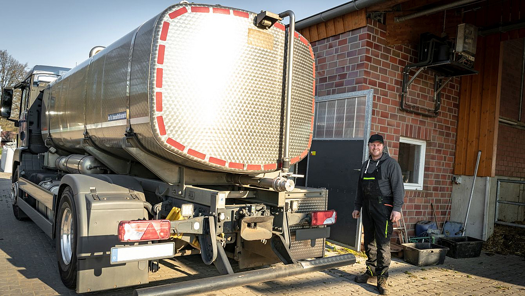 Landwirt steht neben einem Milchtankwagen