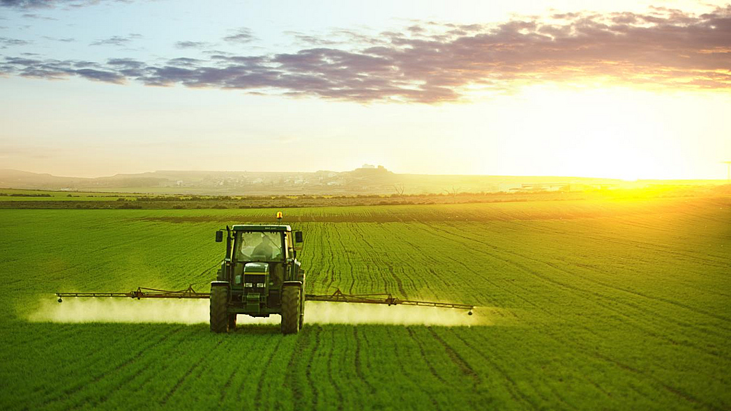 Ein Traktor bringt auf dem Feld Pflanzenschutzmittel aus