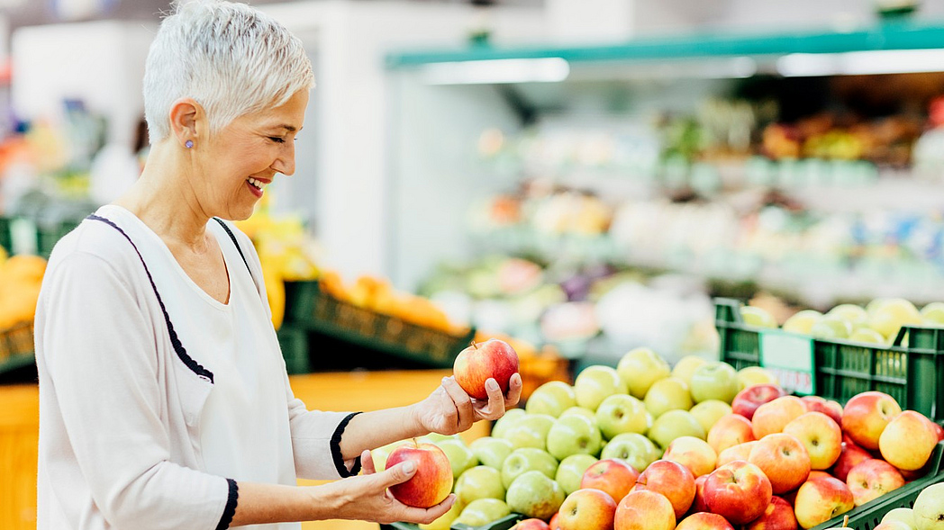 Eine Frau sucht im Supermarkt Äpfel aus. Eine Frau sucht im Supermarkt Äpfel aus.