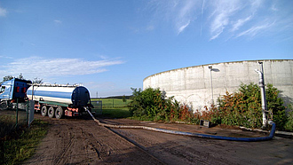 Gülle wird in einen Transporter abgepumpt, rechts ein Güllebehälter
